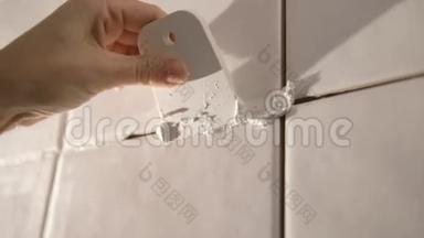 工人在浴室的墙上贴瓷砖。 他的手把瓷砖放在粘合剂上。
